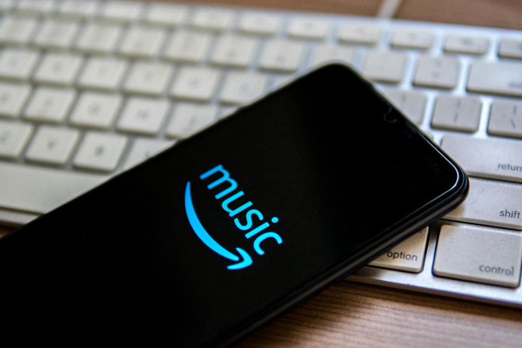 Amazon Music logo displayed on a smartphone that is laying on a computer keyboard