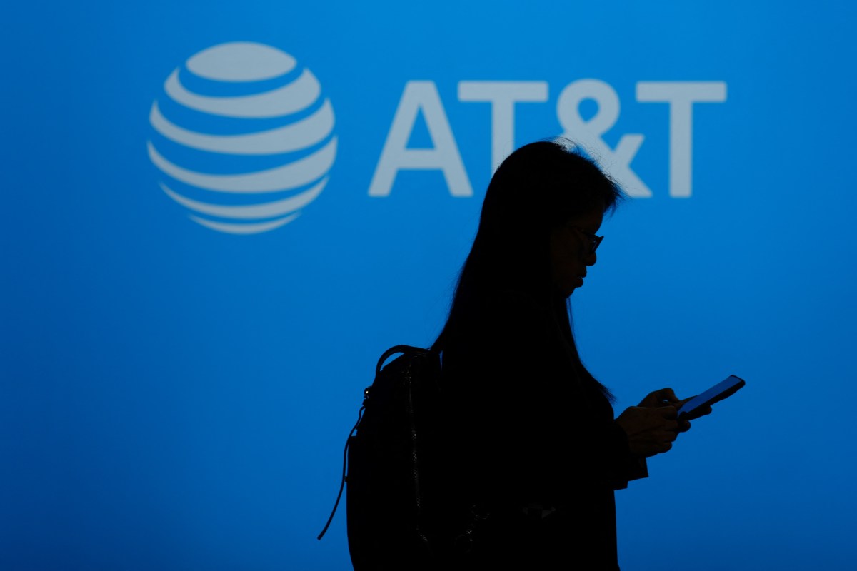 A person walks past the logo of U.S. telecommunications giant AT&T.